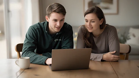 Warmvast-medewerker en klant bekijken samen de subsidieaanvraag achter een laptop aan de keukentafel